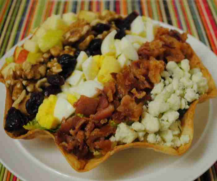 An Apple Cobb Salad with its ingredients striped over the top of an Azteca Salad Shell.