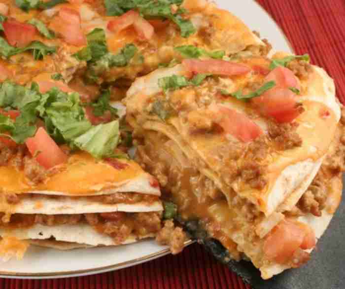A Mexican Pizza with a slice cut out and being pulled away, allowing you to see the inside.