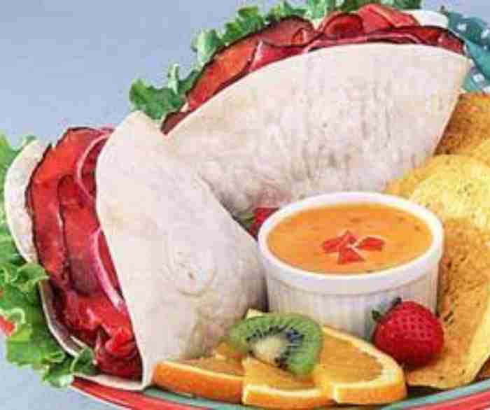 Roast beef tortilla wraps next to a small bowl of queso.