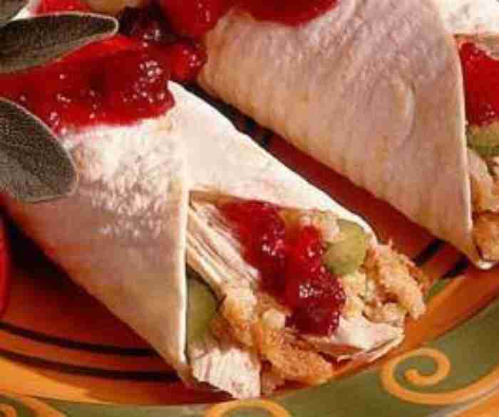 Two turkey cranberry wraps on a green and yellow plate.