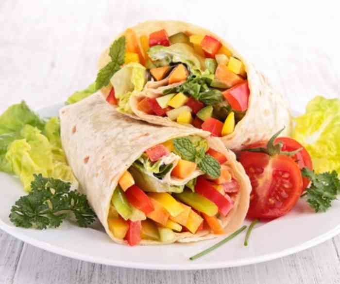 A cheese & veggie wrap cut in half on a plate.