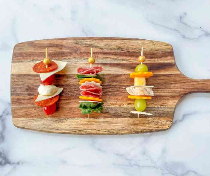 Three Tortilla Sandwich Kabobs on a wooden cutting board atop a marble table.