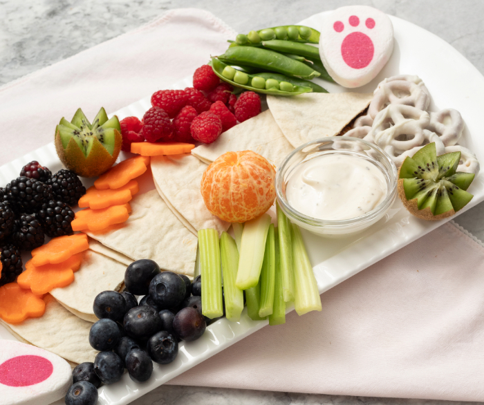A spring picnic board with tortilla slices in the middle.